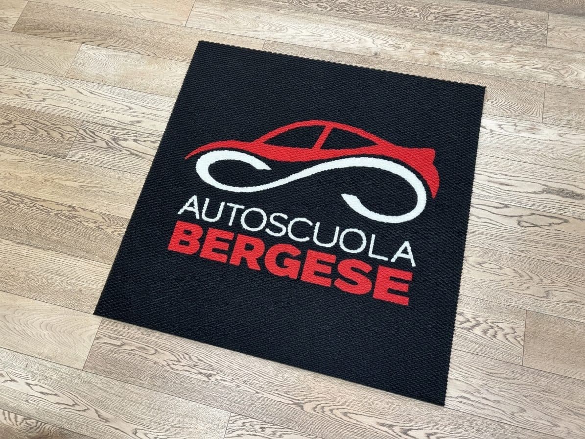Crni otirač Kiko s umetnutim crveno-bijelim logotipom autoškole